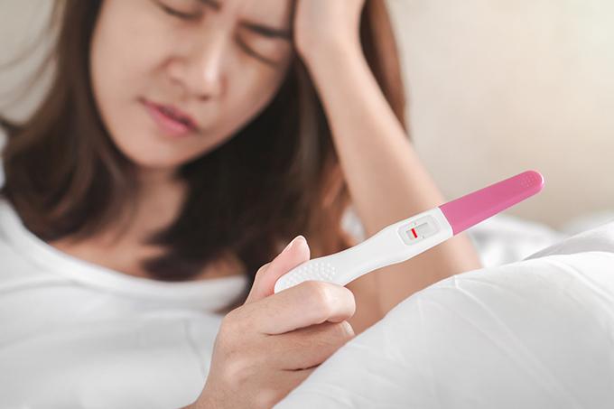 Woman Looking Sad at Pregnancy Test Kit